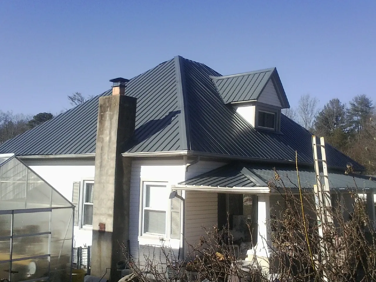 Dark blue standing seam metal roof on a white farmhouse with dormer — Slate & Tile Roof Repair by Roofing Brothers in Mine Hill