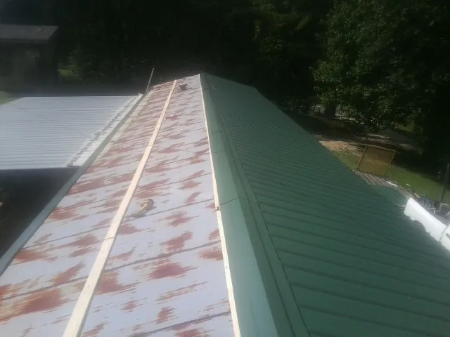 Old rusted panels beside newly installed green metal roofing — Wind Damage Roof Repair by Roofing Brothers in Mine Hill