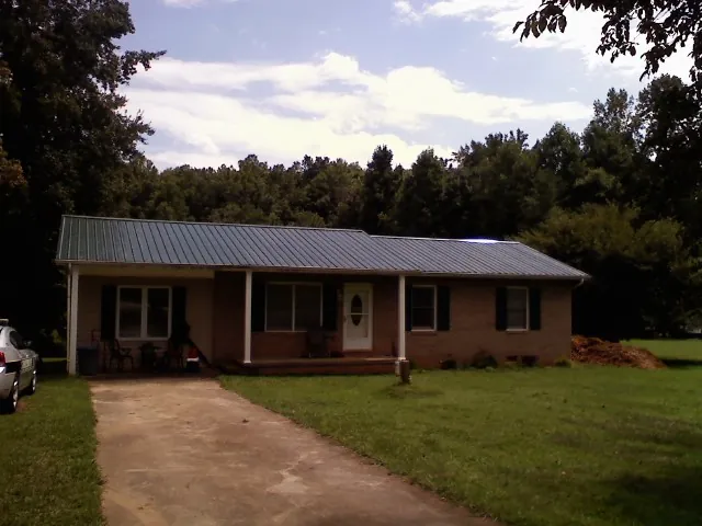 Dark green metal roof on a brick ranch with a covered porch in Mine Hill