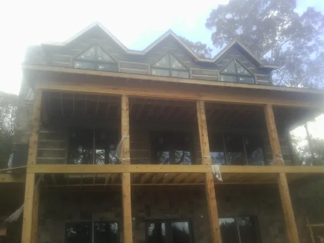 Dormers and porch framing on a large log home under construction — Roof Coating work by our crew in Mine Hill