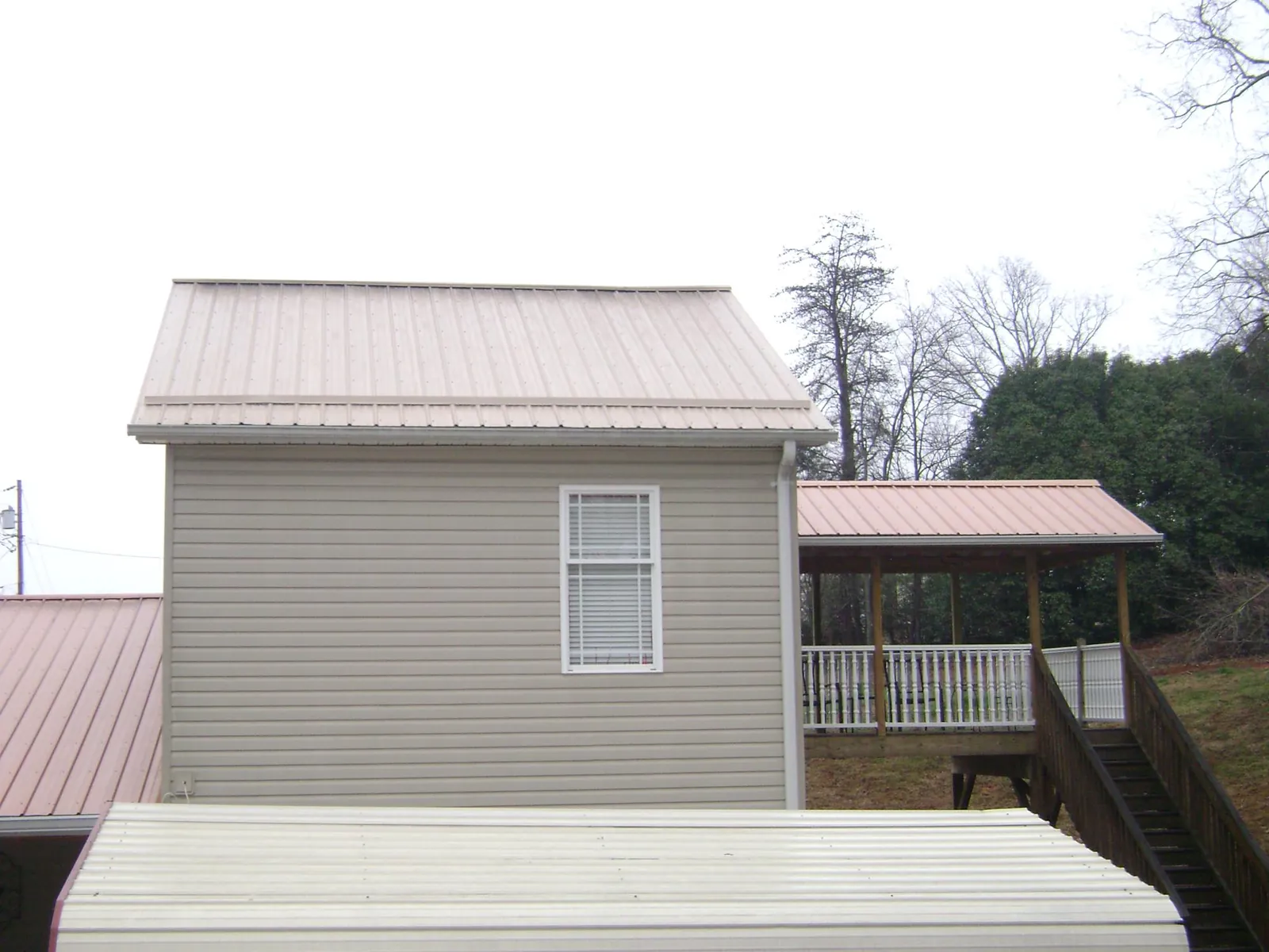 Tan metal roofs on a two story addition and attached porch, from a Roof Replacement job in Mine Hill