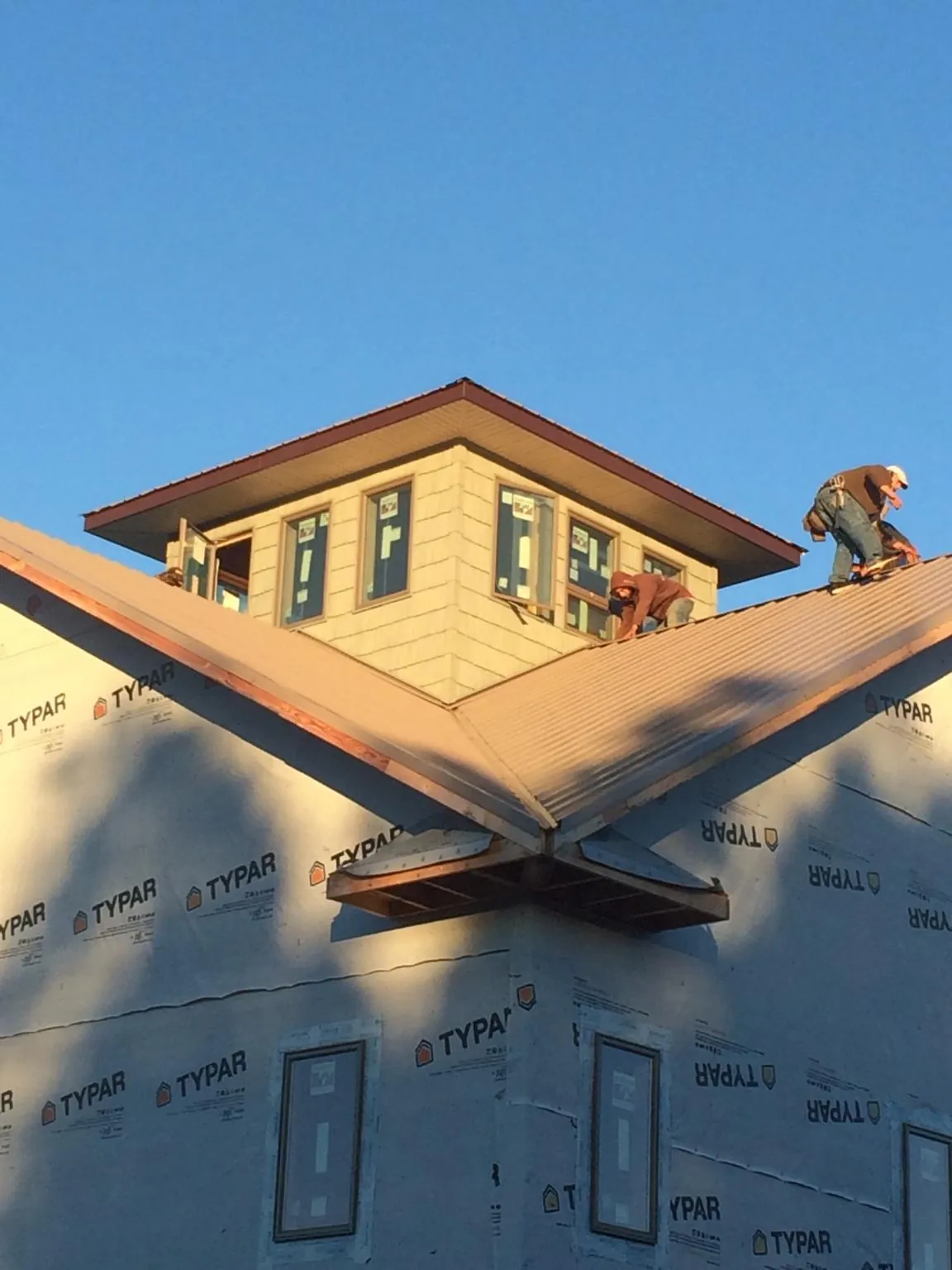 Roofers working around a rooftop cupola on a new metal roof at sunset — Roof Waterproofing in Mine Hill by Roofing Brothers